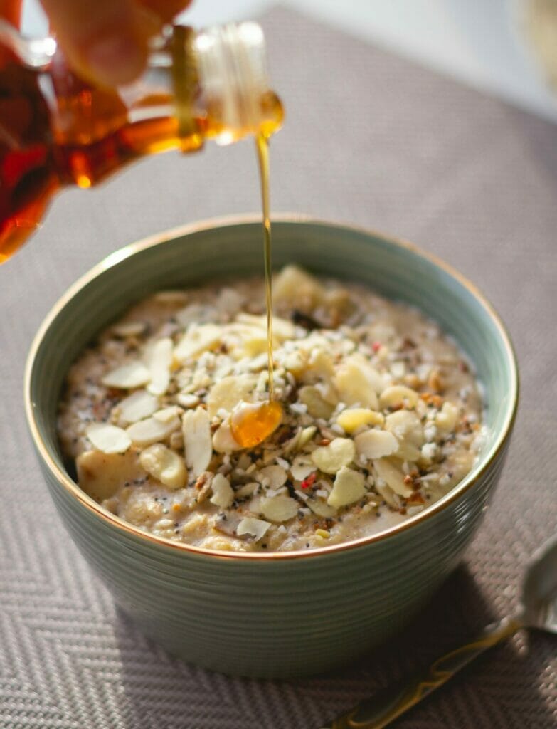 photo of oatmeal with sliced nuts and maple syrup